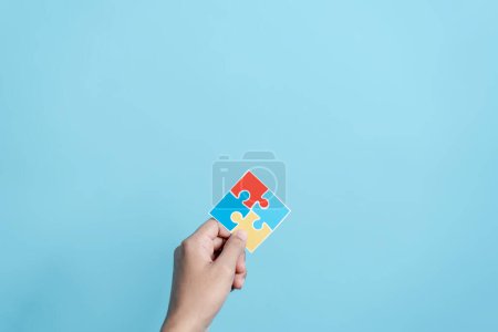 Photo for Hand holding Color puzzle symbol of awareness for autism spectrum disorder family support. Father, Mother, Children holding jigsaw puzzle Autism World Awareness Day. - Royalty Free Image