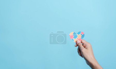 Photo for Hand holding Awareness heart jigsaw puzzle, Color puzzle symbol of awareness for autism spectrum disorder family support. Autism World Awareness Day. - Royalty Free Image