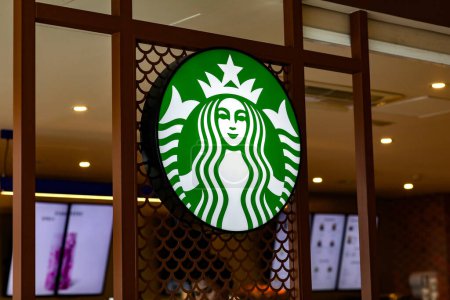 Foto de Valencia, España: 18 de marzo de 2023: Logo verde de marca Starbucks con sirena de dos colas dentro de coffeeshop. Starbucks Corporation es una cadena multinacional de cafeterías y reservas de tostado. - Imagen libre de derechos