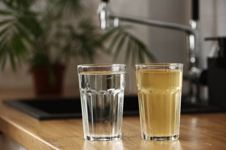 Hauswasserfiltersystem in trinkbarem Zustand. Glas klares Wasser nach der Umkehrosmosefilterung und Glas schmutziges Wasser auf der Tischplatte in der Küche. Beweise für Verunreinigung des Leitungswassers.