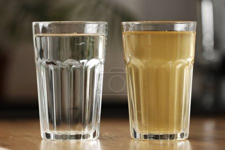 Sistema de filtración de agua de la casa a condición potable. Un vaso de agua clara después de la filtración de osmos inversa y un vaso de agua sucia en la mesa en la cocina. Pruebas de contaminación del agua del grifo.