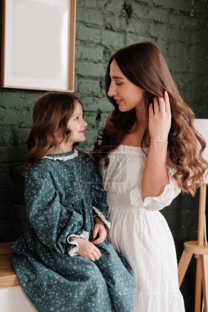 Photo for Mother's day. Sensitive young mom embraces her little adorable daughter at home. Trust, support and love between mommy and child. Loving family enjoy tender sweet moments and tight hugs. Children day. - Royalty Free Image