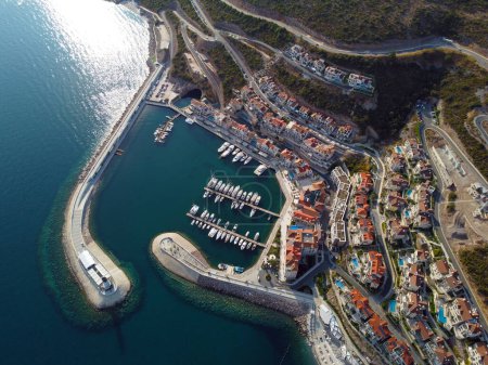 Luftaufnahme der Bucht von Lustica, Adria, Montenegro. Blick von oben auf Gebäude, Harbor Marina mit festgemachten Booten und Yachten und Leuchtturm vor der Kulisse der Berge. Neues modernes Luxus-Resort.