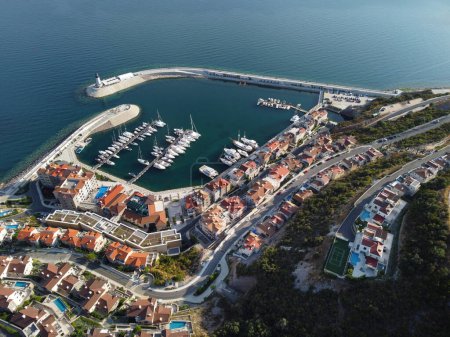 Luftaufnahme der Bucht von Lustica, Adria, Montenegro. Blick von oben auf Gebäude, Harbor Marina mit festgemachten Booten und Yachten und Leuchtturm vor der Kulisse der Berge. Neues modernes Luxus-Resort.