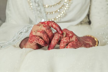 Hands of the bride and groom in a wedding dress with henna