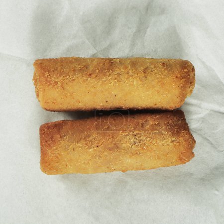Crispy fried croquettes on baking paper, top view
