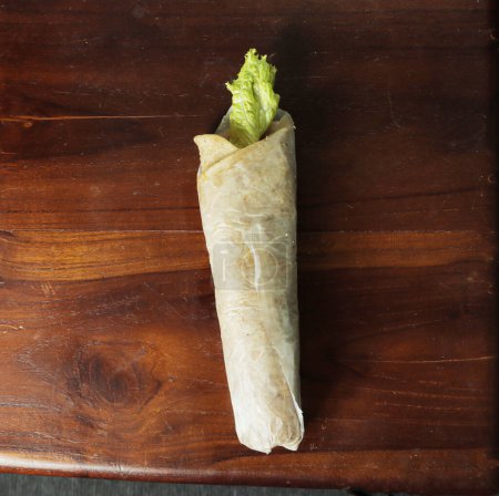 Shawarma with cabbage on a wooden tray.