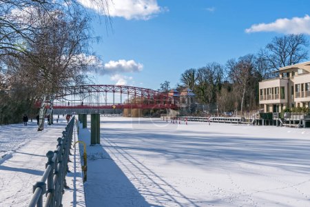 Téléchargez les photos : Berlin, Allemagne - 12 février 2021 : Ruisseau gelé Tegeler Fliess avec son pont Haven (Sechserbruecke) en treillis d'acier protégé par le patrimoine et les habitants qui travaillent le long d'un sentier côtier - en image libre de droit