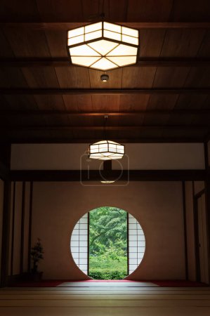 Téléchargez les photos : Vue sur les feuilles vertes de la petite fenêtre ronde dans la chambre japonaise. Oriental fond intérieur - en image libre de droit