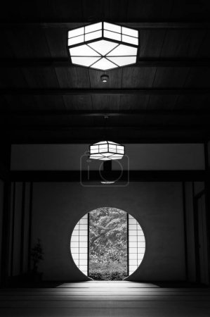 Téléchargez les photos : Vue sur les feuilles vertes de la petite fenêtre ronde dans la chambre japonaise. Oriental fond intérieur - en image libre de droit