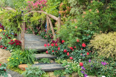 Foto de Puente de madera viejo en hermoso jardín de flores en temporada de primavera - Imagen libre de derechos
