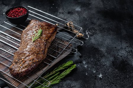 Téléchargez les photos : Barbecue grillé tri pointe de bœuf steak sur un gril. Fond noir. Vue de dessus. Espace de copie. - en image libre de droit