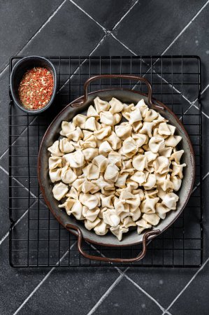 Foto de Cooking Manti Dumpling, raw food in a steel tray. Black background. Top view. - Imagen libre de derechos