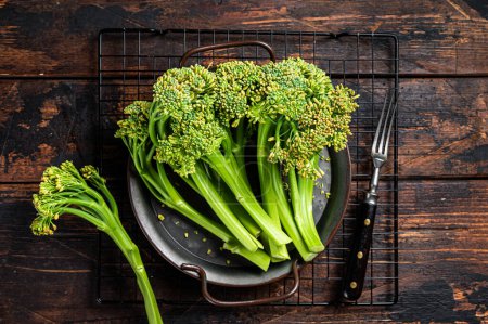 Foto de Fresh Raw Organic Broccolini cabbage in a steel tray. Wooden background. Top view. - Imagen libre de derechos