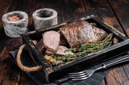 Téléchargez les photos : Grillé Tri Tip steak, surlonge de bœuf dans un plateau avec des herbes. Fond en bois. Vue du dessus. - en image libre de droit