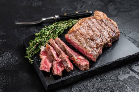 Téléchargez les photos : Griiled on BBQ sliced Striploin marbled beef meat steak. Black background. Top view. - en image libre de droit