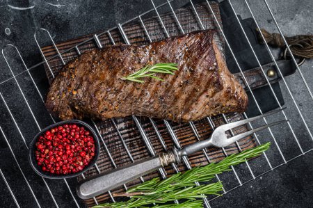 Téléchargez les photos : Barbecue grillé tri pointe de bœuf steak sur un gril. Fond noir. Vue du dessus. - en image libre de droit