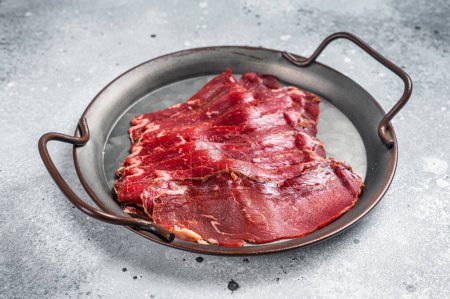 Photo for Sliced basturma, cured beef meat in steel tray. Gray background. Top view. - Royalty Free Image