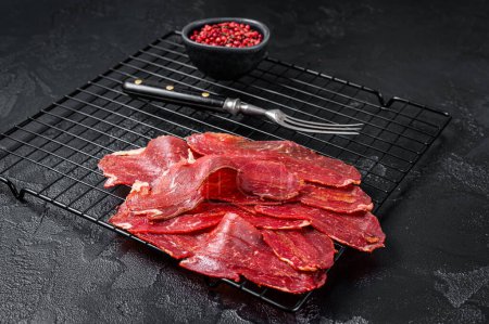 Photo for Dried sliced basturma, cured beef meat ready for eat. Black background. Top view. - Royalty Free Image