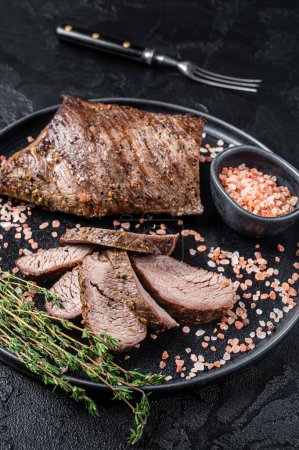 Téléchargez les photos : Barbecue wagyu vieilli sec Tri Tip steak de boeuf sur une assiette avec du sel rose. Fond noir. Vue du dessus. - en image libre de droit