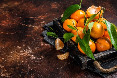 Fresh mandarin oranges or tangerines fruits with leaves. Dark background. Top view. Copy space.