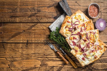 Flammkuchen or tarte flambee with cream cheese, bacon and onions. Wooden background. Top view. Copy space.
