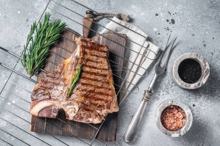 Téléchargez les photos : Viande de bœuf grillée au porterhouse T-bone Steak sur un gril avec des épices. Fond gris. Vue du dessus. - en image libre de droit