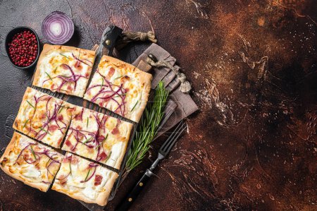 Foto de French tarte flambee with cream cheese, bacon and onions. Flammkuchen from Alsace region. Dark background. Top view. Copy space. - Imagen libre de derechos