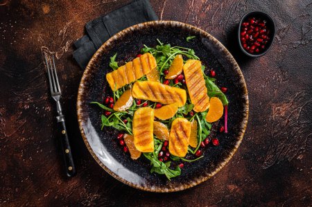 Photo for Summer Salad with grilled Halloumi cheese, arugula, oranges and pomegranate. Dark background. Top view. - Royalty Free Image