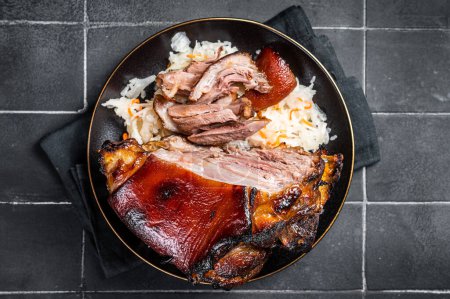 Photo for Roast Pork Ham Hock, knuckle with Sauerkraut on a plate. Black background. Top view. - Royalty Free Image