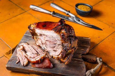 Photo for Roasted pork Shank, knuckle on a wooden board. Orange background. Top view. - Royalty Free Image