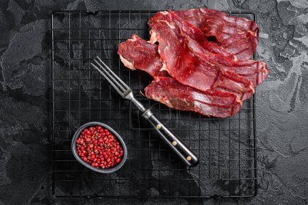 Photo for Dried sliced basturma, cured beef meat ready for eat. Black background. Top view. - Royalty Free Image