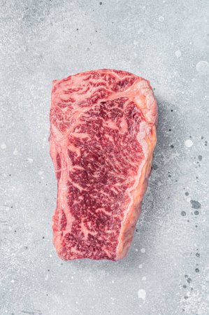 Raw Wagyu striploin or New york steak on a butcher table. Gray background. Top view.