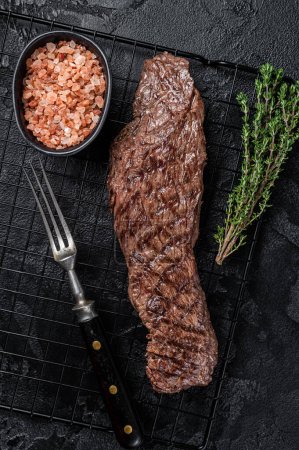 Téléchargez les photos : Grilled meat steak Machete skirt on a rack. Black background. Top view. - en image libre de droit