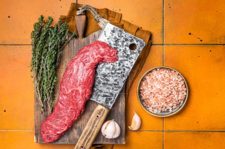 Téléchargez les photos : Fresh Raw Machete beef meat steak or hanging tender cut on butcher cutting board. Orange background. Top view. - en image libre de droit