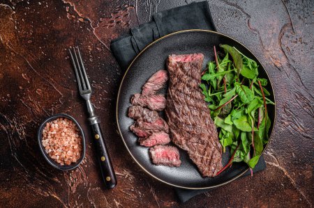 Téléchargez les photos : Juicy Grilled Machete jupe viande de bœuf steak sur assiette avec salade. Fond sombre. Vue du dessus. - en image libre de droit