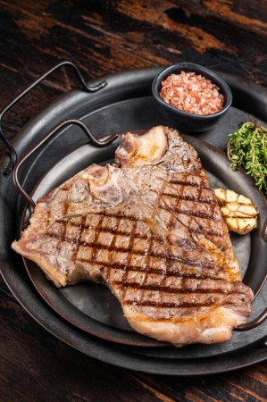 BBQ Grilled T-bone or Porterhouse beef meat Steak on a steel tray with herbs. Wooden background. Top view.
