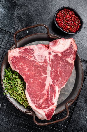 Frisches, rohes T-bone marmoriertes Rindfleisch Steak auf einem Stahlblech. Schwarzer Hintergrund. Ansicht von oben.