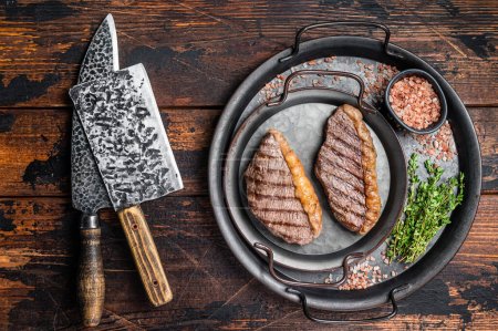 Photo for BBQ Grilled top sirloin steak, cup rump beef meat steak in a steel tray. Wooden background. Top view. - Royalty Free Image