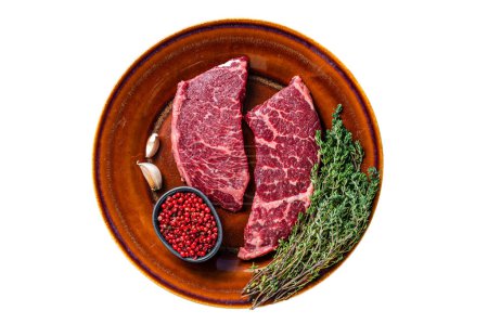 Fresh Raw denver or top blade meat steak on a rustic plate with thyme. Isolated on white background