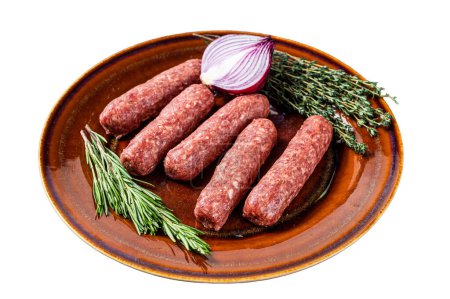 Rohe Kofta-Fleischspieße auf einem Teller mit Kräutern. Isoliert auf weißem Hintergrund