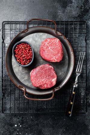 Téléchargez les photos : Dry aged Raw steaks fillet Mignon, Beef tenderloin. Black background. Top view. - en image libre de droit