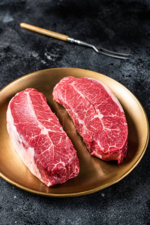 Téléchargez les photos : Raw Shoulder Top Blade steaks de viande de bœuf sur une assiette. Fond noir. Vue du dessus. - en image libre de droit