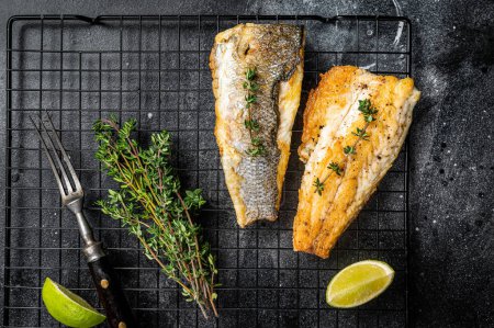 Photo for Grilled sea bass fillet with lime and thyme. Black background. Top view. - Royalty Free Image