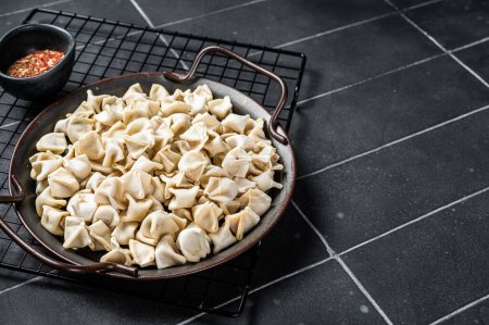Foto de Cocinar Manti Dumpling, comida cruda en una bandeja de acero. Fondo negro. Vista superior. Copiar espacio. - Imagen libre de derechos