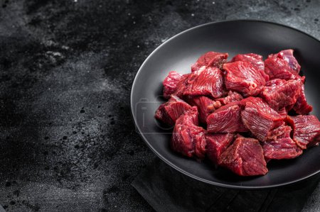 Raw Diced game meat of wild venison dear. Black background. Top view. Copy space.