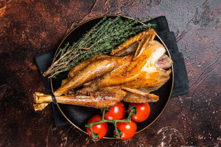Téléchargez les photos : Roast guinea fowl with herbs and spices, cooked game bird. Dark background. Top view. - en image libre de droit
