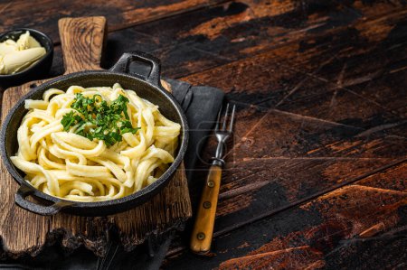 German Spaetzle egg Noodles with Butter and Parsley in a skillet. Wooden background. Top view. Copy space.