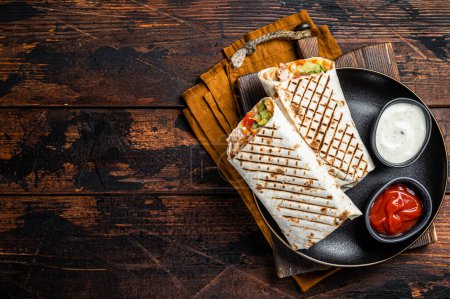 Téléchargez les photos : Shawarma, Shaurma chicken roll with vegetable salad. Wooden background. Top view. Copy space. - en image libre de droit