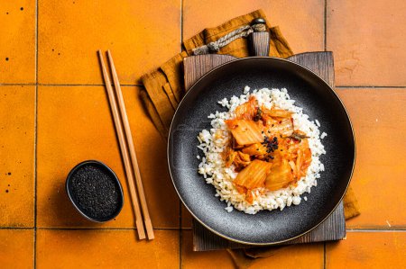 Photo for Kimchi with pork on cooked rice, traditional Korean cuisine. Orange background. Top view. - Royalty Free Image